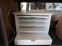 Front view of white desktop organizer showing four trays and open bottom drawer