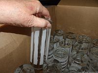 box of tumblers, hand holding glass with vertical white stripes