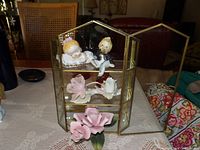 Cabinet open displaying figurines and roses