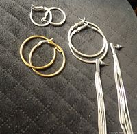 All three earring pairs laid out: gold hoops, silver hoops, silver tassel dangles