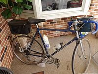 Full left-side view of bicycle showing frame, wheels, drivetrain, rear bag, one water bottle