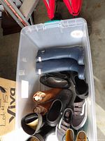 Plastic bin showing Hunter rain boots, Crocs, Vans sneakers, suede boots and others