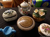 All six trinket boxes grouped on black surface showing variety of shapes and finishes