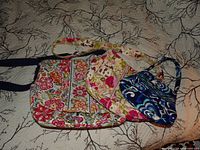 Three Vera Bradley quilted cotton bags displayed on bedspread