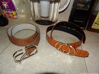 Both belts laid flat showing buckles and leather finish