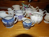 Group view of all twelve miniature creamers showing assorted designs