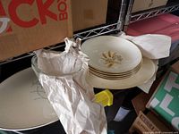 Stack of wheat motif plates, clear glass bowl beside