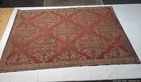 Full top view of rectangular rust and brown damask rug