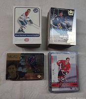Four stacks of hockey cards including sleeved stack and visible Henri Richard, Mario Lemieux, Joe Sakic cards