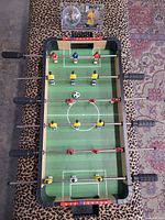 Top view of tabletop foosball game showing player layout, ball, Neymar collectible case