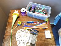 Overall lot on table showing bin with tools, ribbon spool, notebooks, pipe cleaners and assorted items