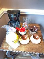 Entire lot on small table showing coffee maker, pitcher, cups, bowls, measuring spoons, plates