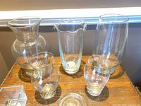 Group view of multiple clear glass vases on tabletop