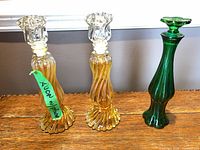 Two amber swirl Avon pressed-glass perfume bottle candlesticks with stoppers and one green pressed-glass candlestick perfume bottle