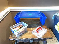 Overall view showing blue plastic lap desk on table, clear storage box with coloured pencils, separate lid