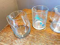 Rounded plain glass mug beside cylindrical decal mug