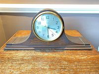 Front view showing entire wooden tambour mantel clock with brass bezel