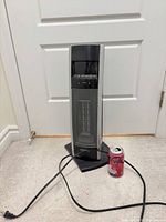 Full view of tower heater on base with power cord and soda can for scale