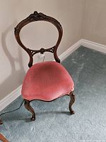 Front view of carved balloon-back chair with pink velvet seat
