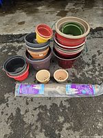 Stacks of assorted planter pots and packaged burlap roll on pavement