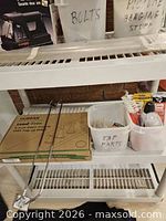 Shelf with boxed Hurran faucet, grabber tool, bin of tap parts and sealant tubes visible