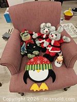 Group shot of all plush characters, penguin decoration and snowman tealight holder on chair