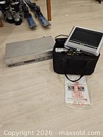 Overall view of Emerson VHS player, Kawasaki portable DVD system in carry bag, manual visible