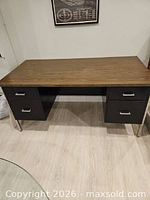 Front view of metal desk showing wood-grain top and drawers