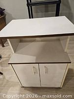 Front view of white laminate microwave stand with open shelf and cabinet doors closed