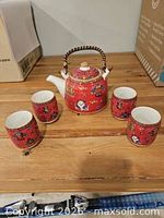 full view of teapot and four cups on tabletop