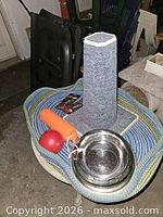 All five items on view: woven bed, scratching post, stainless dish, red ball, orange retrieve toy