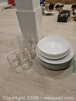 Stack of dinner plates, pair of bowls, tall and short glasses grouped together