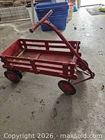 Side view of red metal pull wagon showing slatted sides, handle, wheels