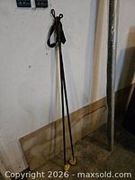 Full view of both black Exel ski poles leaning against wall