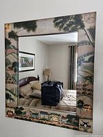 Front view of hand painted tole mirror hung on wall