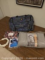 Overall lot with duffel, packaged pillow, laundry bag, pouch and lei