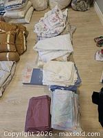 Multiple folded sheet sets, comforters and mattress covers on floor