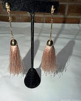Full view of both tassel earrings hanging from stand