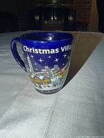 Front view showing text and village illustration on mug