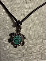 Close-up of turtle pendant showing turquoise shell segments and rhinestones