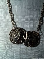 Close-up of gold-tone chain and two-coin pendant