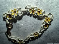 Overall view of the white metal bracelet showing floral enamel details and clasp