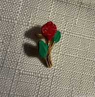 Front view of red enamel rose pin with goldtone stem and green leaves