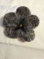 front view of grey felt flower brooch showing five petals and yellow center