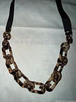 Full view of necklace showing plastic links and ribbon straps