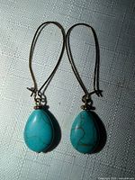 Front view showing both earrings, gold-tone hooks, teardrop turquoise stones