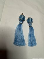 Front view of both baby blue tassel earrings showing studs, pearls and tassels