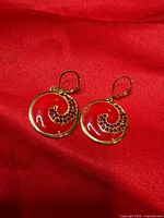 front view showing red enamel and rhinestone swirl design