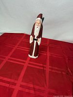 Front view of carved wooden Santa figurine showing face, beard and coat colors