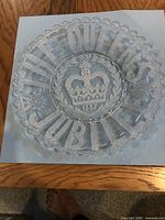 Top view of clear pressed glass platter showing crown motif and lettering